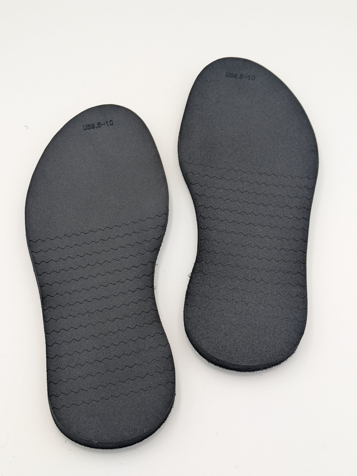 Pair of black shoe outsoles on a white background
